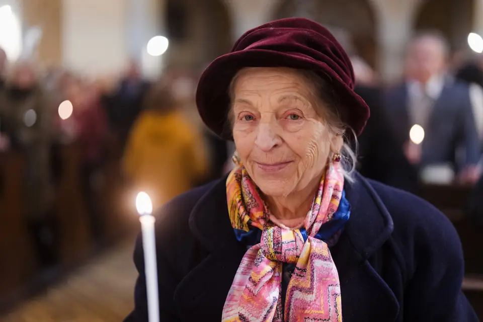 Starší žena se svíčkou při velikonoční vigilii
