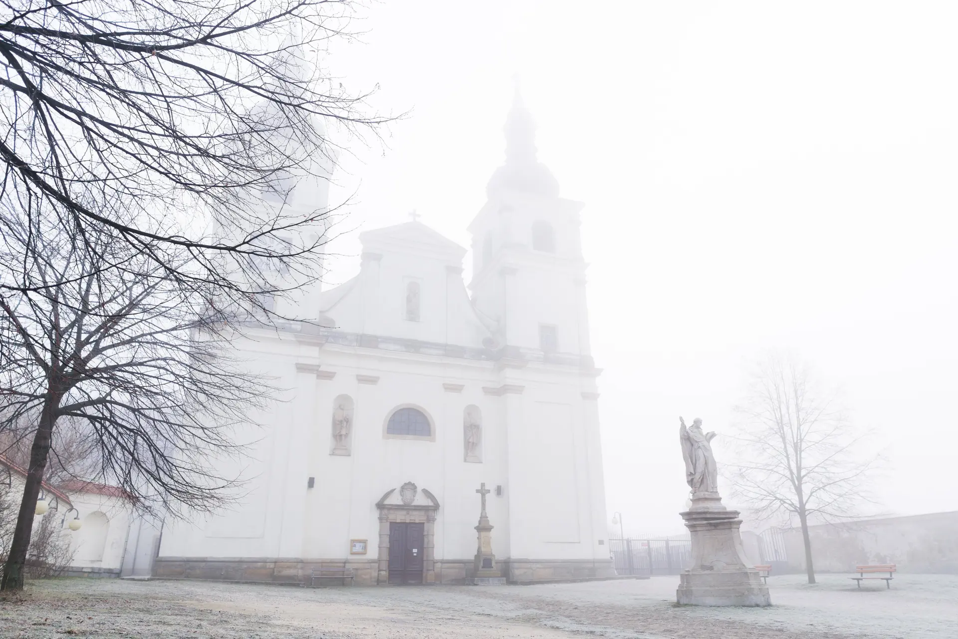 Dvojvěžové průčelí dominikánského kostela v mlze