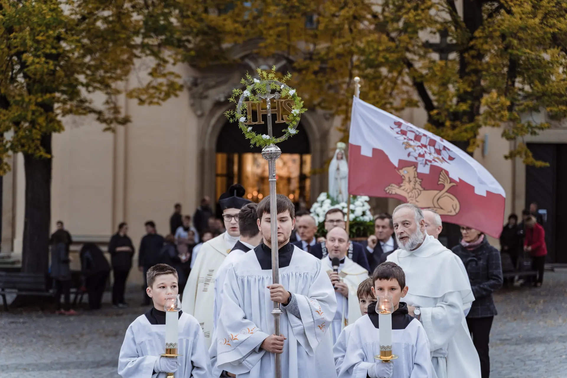 Průvod s praporem a ministranty před kostelem
