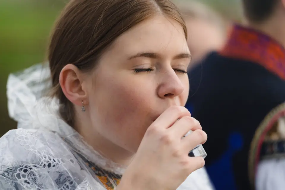 Dívka v kroji ochutnává z kalíšku