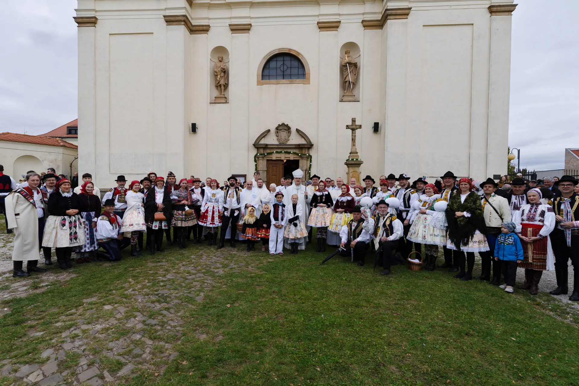 Kněží, ministranti a krojovaní poutníci před dominikánským kostelem