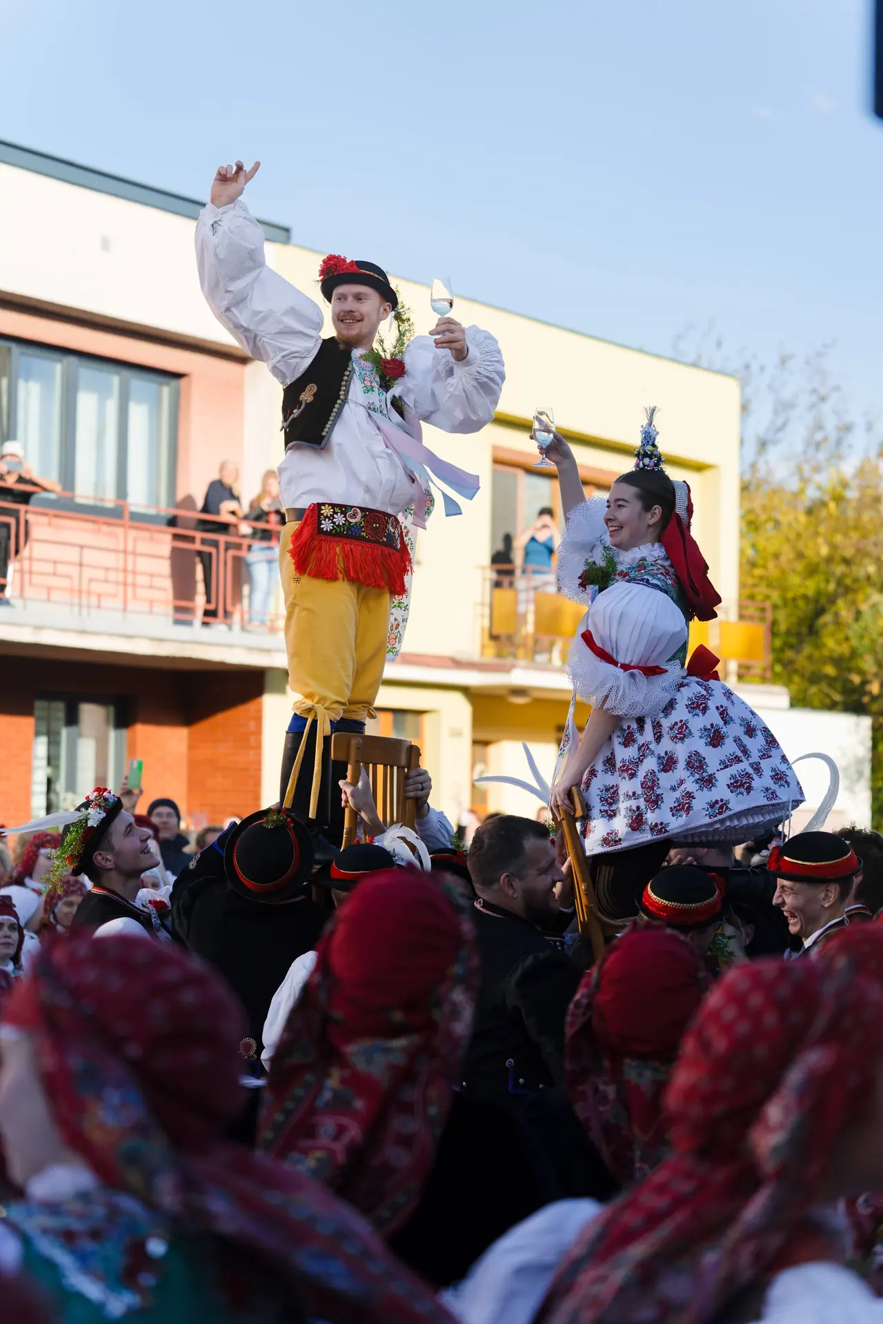 Stárek a stárka vyzdvižení nad hlavy krojovaných